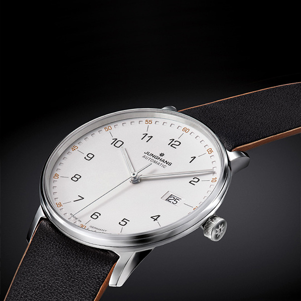 Juwelier-Wagner-Madler-Uhren-Junghans-Kollektion-Form-ansicht-2 Eine elegante Armbanduhr aus der Junghans Form Kollektion mit weißem Zifferblatt, schwarzem Lederarmband und silbernem Gehäuse. Das Zifferblatt zeigt schwarze arabische Ziffern, ein Datumsfenster bei 3 Uhr und den Markennamen „Junghans“ sowie „Automatic“ unter der 12-Uhr-Markierung.