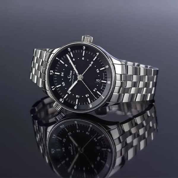 Juwelier-Wagner-Madler-Uhren-Sinn-Kollektionen-finanzplatz-6096 Eine elegante Armbanduhr mit silbernem Metallarmband und schwarzem analogem Zifferblatt, das Stunden-, Minuten- und Sekundenmarkierungen auf einer reflektierenden dunklen Oberfläche anzeigt. Als Teil der Sinn Finanzplatz Kollektion besticht diese Uhr durch ein minimalistisches, elegantes Design.