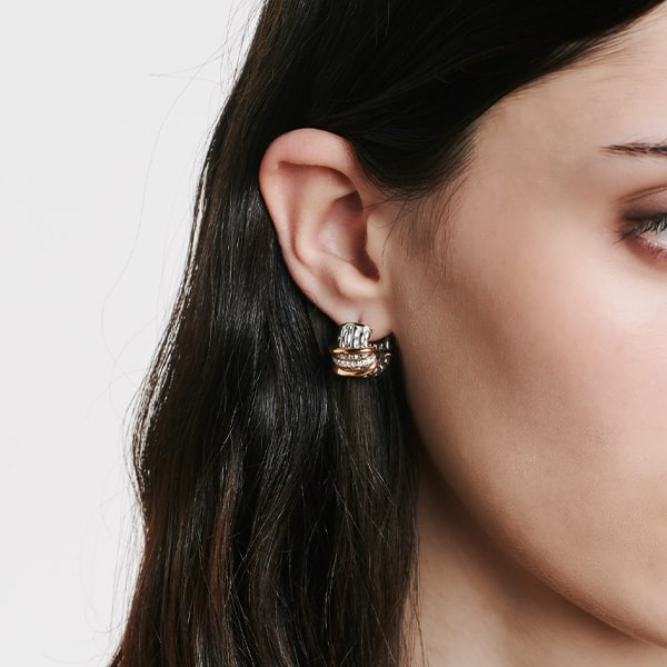 FOPE © 2024 Nahaufnahme des rechten Ohrs einer Frau, das mit einem silber- und goldfarbenen Fope Ohrschmuck-Ohrring geschmückt ist. Die Frau hat dunkles, glattes Haar und der Hintergrund ist weiß.