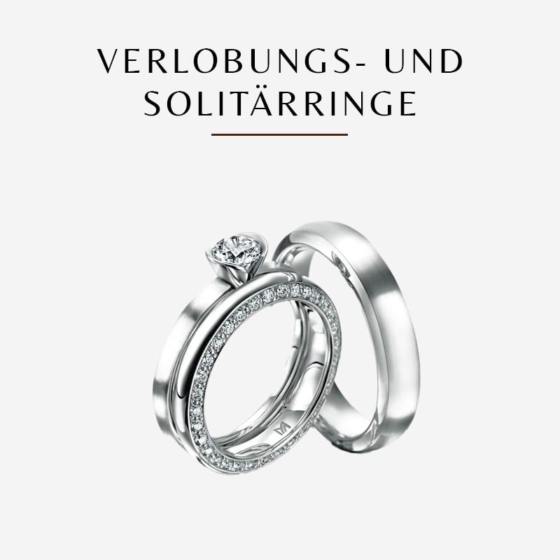 Abgebildet ist ein Paar Meisterringe: ein Solitär-Verlobungsring mit einem auffälligen Diamanten oben drauf, der andere ist ein Ehering, der mit kleinen Diamanten besetzt ist. Der deutsche Text über den Ringen lautet „VERLOBUNGS- UND SOLITÄRRINGE“.