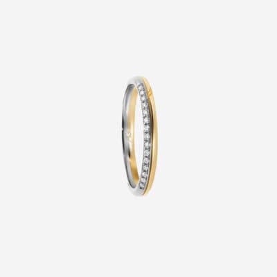 © Juwelier Wagner-Madler Eine Nahaufnahme eines schmalen, eleganten Rings mit zweifarbigem Design. Eine Hälfte ist Silber, die andere Hälfte Gold, und in der Mitte verläuft eine Reihe kleiner funkelnder Diamanten, die einen auffälligen, luxuriösen Kontrast bilden. Dieses Stück könnte problemlos in jedes Schmucklexikon aufgenommen werden. Der Hintergrund ist schlicht weiß.