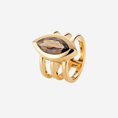 © Juwelier Wagner-Madler Ein Goldring mit einem einzigartigen Dreifach-Band-Design, in dessen Mitte ein horizontal angeordneter brauner Edelstein im Marquise-Schliff vor einem schlichten weißen Hintergrund angebracht ist, ist ein exquisites Stück, das in jedes Schmucklexikon gehört.