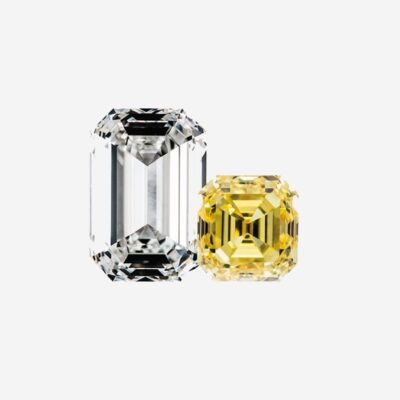 © Juwelier Wagner-Madler Auf einem schlichten weißen Hintergrund sind zwei Edelsteine abgebildet. Der linke Edelstein ist ein größerer, klarer Diamant im Smaragdschliff. Rechts daneben befindet sich ein kleinerer, quadratischer, gelber Diamant. Beide Edelsteine sind in Nahaufnahme dargestellt, wodurch ihre Facetten und Brillanz hervorgehoben werden, als ob sie direkt aus einem Schmucklexikon stammen würden.