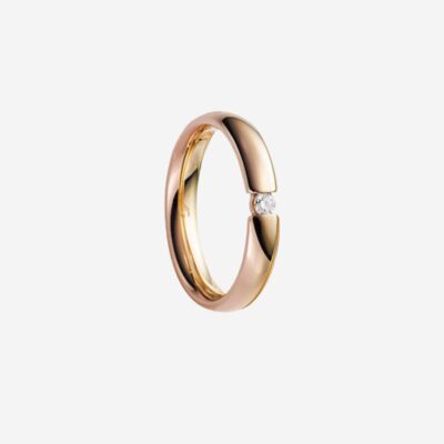 © Juwelier Wagner-Madler Ein eleganter Ring aus Roségold mit modernem, offenem Design weist einen einzelnen kleinen Diamanten zwischen den beiden Enden auf. Der Ring hat eine glatte, polierte Oberfläche und wird vor einem schlichten weißen Hintergrund präsentiert, was die Essenz der Eleganz von Schmucklexikon perfekt einfängt.