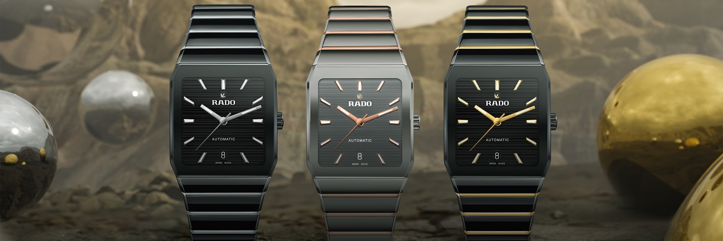 Drei Rado-Uhren werden in einer Reihe präsentiert. Jede hat ein rechteckiges Zifferblatt und ein Metallarmband. Die Uhren unterscheiden sich in der Farbe: Schwarz mit Silber, Dunkelgrau mit Kupfer und Schwarz mit goldenen Akzenten. Im Hintergrund befindet sich eine reflektierende Kugel.