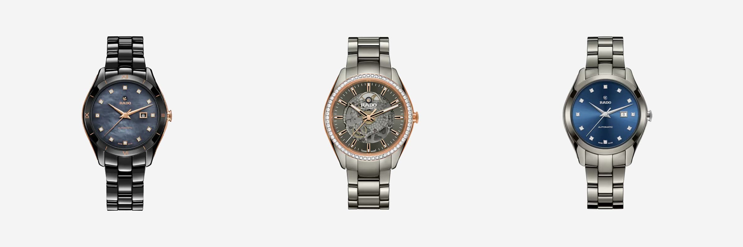 Drei Luxusarmbanduhren werden in einer Reihe ausgestellt. Die linke Uhr hat ein dunkelblaues Zifferblatt mit goldenen Details. Die mittlere Uhr hat ein transparentes Zifferblatt mit roségoldenen Akzenten. Die rechte Uhr hat ein blaues Zifferblatt mit silbernen Details, alles vor einem weißen Hintergrund.