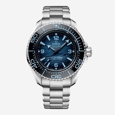 OMEGA © 2024 Eine Omega Seamaster Planet Ocean Ultra Deep-Uhr aus Edelstahl mit blauem Farbverlaufszifferblatt, schwarzer drehbarer Lünette und silbernen Stundenmarkierungen und Zeigern. Mit zwei Zeigersätzen für Stunden, Minuten und Sekunden in seinem 45,5-mm-Gehäuse ist diese Uhr ein Wunderwerk direkt aus dem Uhrenlexikon.