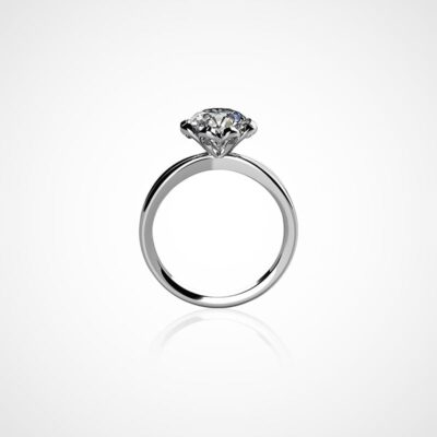 Ein silberner Verlobungsring mit einem einzelnen runden Diamanten an der Oberseite ist vor einem schlichten weißen Hintergrund zu sehen. Der Diamant, der von vier Zinken gehalten wird, funkelt brillant auf dem schlanken und schlichten Ringdesign und ist somit ein perfekter Eintrag in jedes Schmucklexikon.