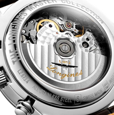LONGINES © 2024 Nahaufnahme der Rückseite einer Luxusarmbanduhr, die ihr kompliziertes mechanisches Uhrwerk zeigt. Zu den Gravuren gehören „THE LONGINES MASTER COLLECTION“, „ALL STAINLESS STEEL“, „SWISS MADE“ und „WATER-“, zusammen mit dem Markennamen „Longines“, der in das Uhrwerk eingraviert ist. Eine kleine Krone ist sichtbar und verkörpert die Pracht des Uhrenlexikons.