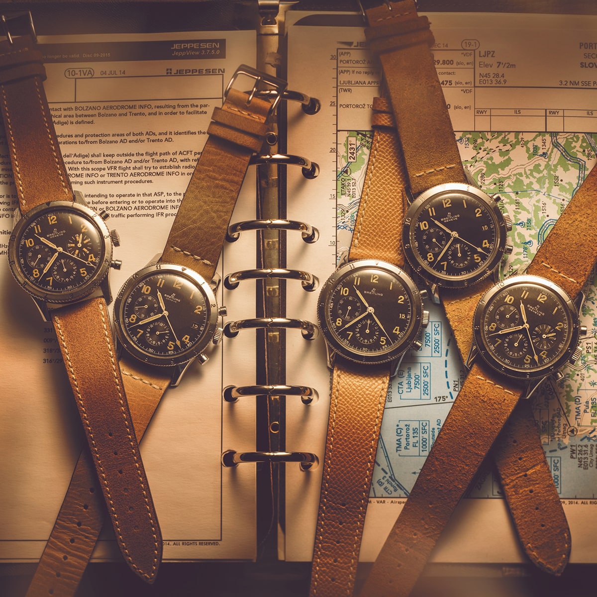 Fünf alte Armbanduhren, darunter eine klassische Breitling mit braunem Lederarmband, sind auf einer offenen Mappe mit Luftfahrtkarten und Notizen angeordnet und schaffen eine nostalgische und zeitlose Atmosphäre.