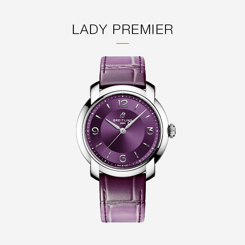 Eine auffällige Breitling Lady Premier Armbanduhr mit violettem Lederarmband und silbernem Gehäuse wird auf einem schlichten, hellen Hintergrund gezeigt, mit dem Text "LADY PREMIER" über der Uhr.