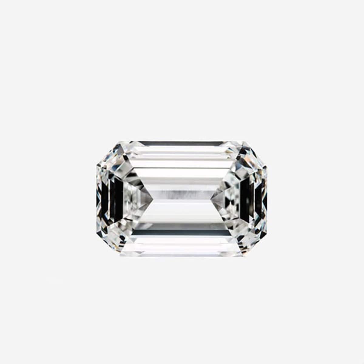 © Juwelier Wagner-Madler e.K. Nahaufnahme eines Diamanten im Smaragdschliff vor einem schlichten weißen Hintergrund. Der Diamant ist symmetrisch mit klar definierten Facetten, die seine Klarheit und Brillanz zur Schau stellen, ein wahres Juwel aus den Seiten des Schmucklexikons.