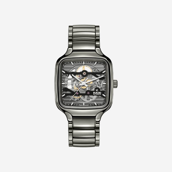 Eine silberne, rechteckige, skelettierte Uhr mit Metallarmband, die ihre internen Zahnräder und Mechanismen offenlegt. Die Marke "Rado" ist auf dem transparenten Zifferblatt mit silbernen Indexen und Zeigern sichtbar.