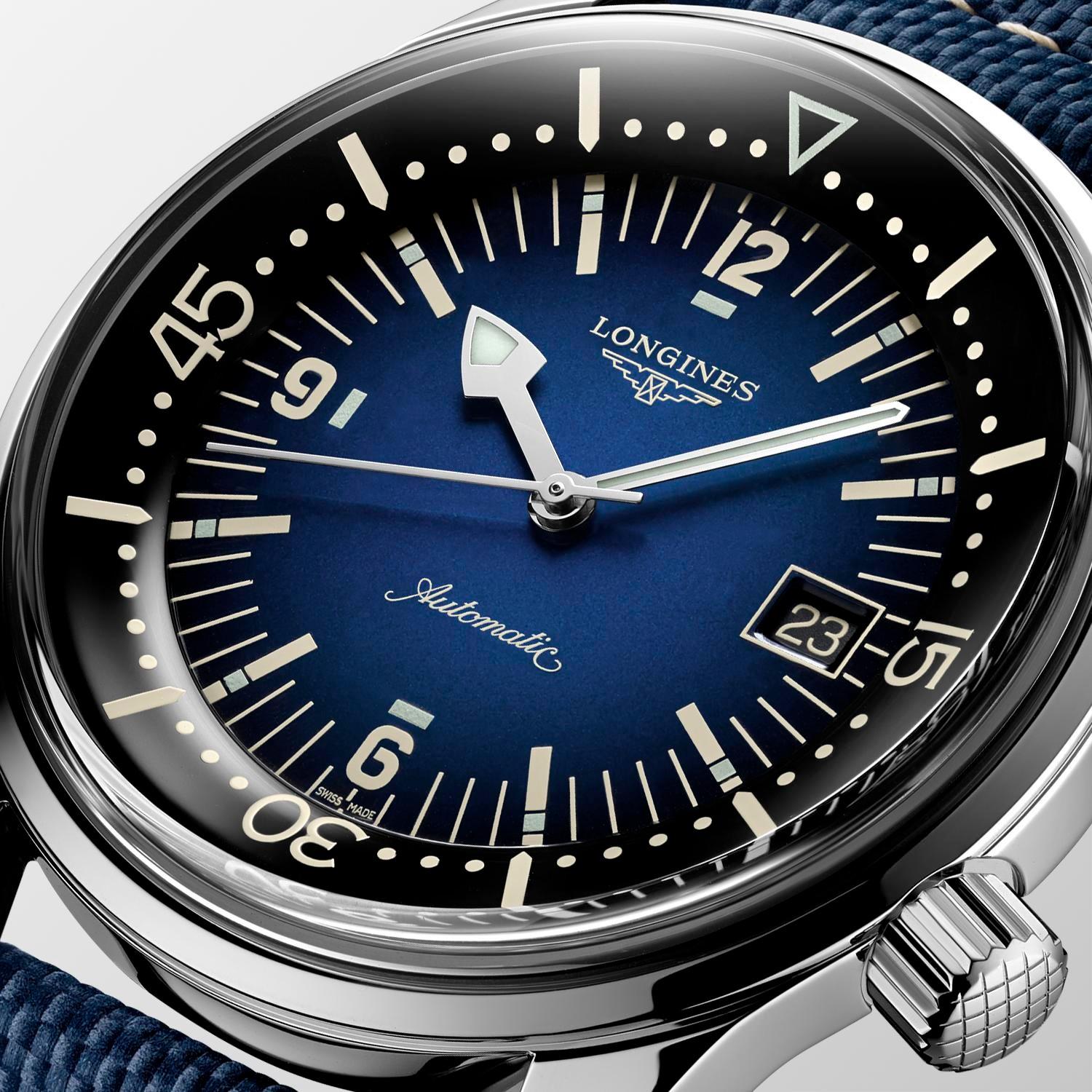 Nahaufnahme der THE LONGINES LEGEND DIVER WATCH 42MM mit blauem Zifferblatt mit weißen Indexen, Datumsfenster bei 3 Uhr, silbernen Zeigern, schwarzer Lünette mit fetten Ziffern und strukturiertem blauem Armband.