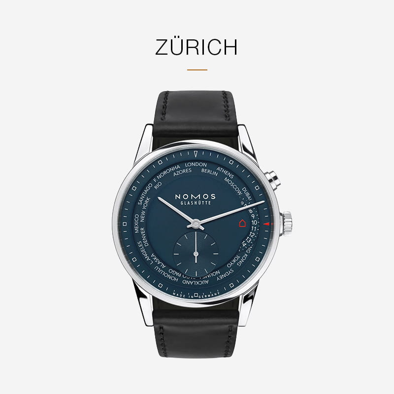 Eine NOMOS Glashütte Zürich-Armbanduhr mit dunkelblauem Zifferblatt, silbernem Gehäuse, schwarzem Lederarmband und Weltzeitzonen auf dem Zifferblatt. Über dem edlen NOMOS Glashütte-Zeitmesser steht auf weißem Grund "Zürich".