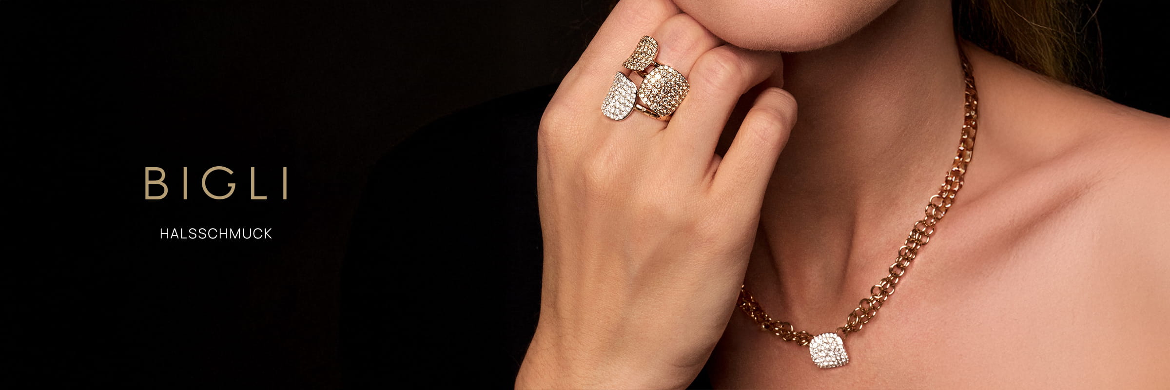 Eine Frau trägt eine goldene Halskette und zwei goldene Ringe, alle mit quadratischen, diamantbesetzten Motiven. Auf schwarzem Hintergrund hebt der Text "Bigli Halsschmuck" hervor.