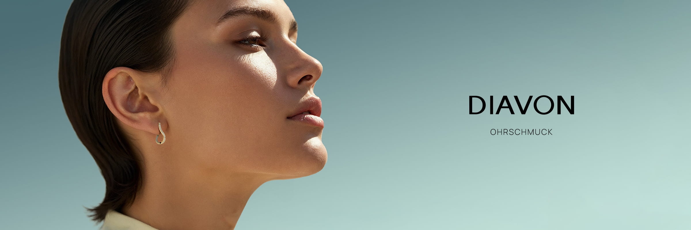 Eine Frau mit kurzen dunklen Haaren und einem kleinen Ohrring blickt nach oben gegen einen klaren blauen Himmel. Neben ihr erscheint der Schriftzug "Diavon Ohrschmuck", der die Eleganz ihres Schmucks unterstreicht.