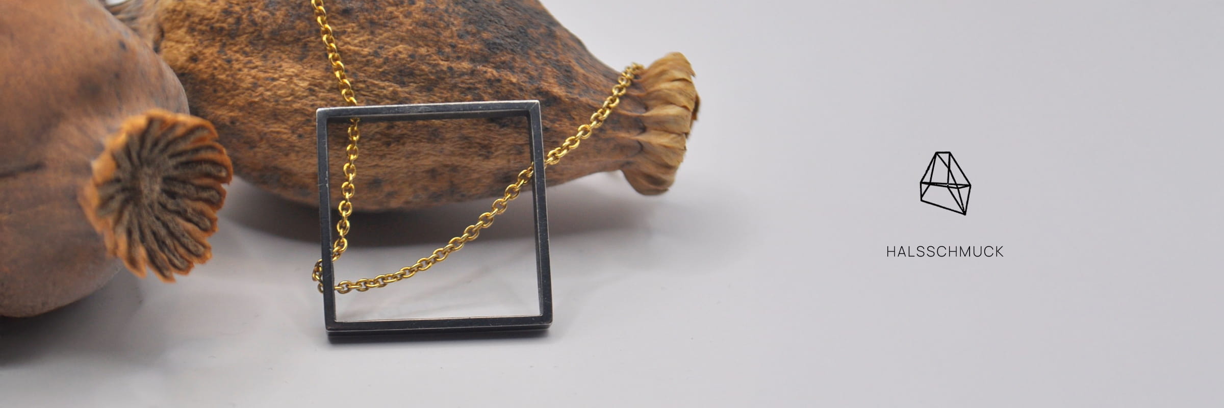 Eine goldene Halskette mit einem quadratischen schwarzen Anhänger ist über eine getrocknete Mohnschote drapiert. Auf dem hellgrauen Hintergrund sind ein geometrischer Anhänger und das Wort "HALSSCHMUCK" abgebildet, was die Eleganz von DOPPELLUDWIG Halsschmuck unterstreicht.