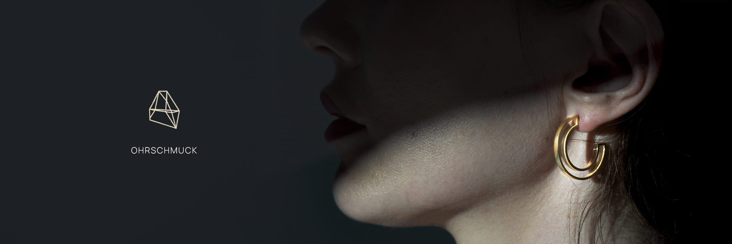 DOPPELLUDWIG © 2026 Nahaufnahme des Ohrs einer Person, die einen dicken, goldenen Ohrring trägt. Die linke Seite zeigt das DOPPELLUDWIG-Schmucklogo und das Wort "Ohrschmuck" auf dunklem Hintergrund.