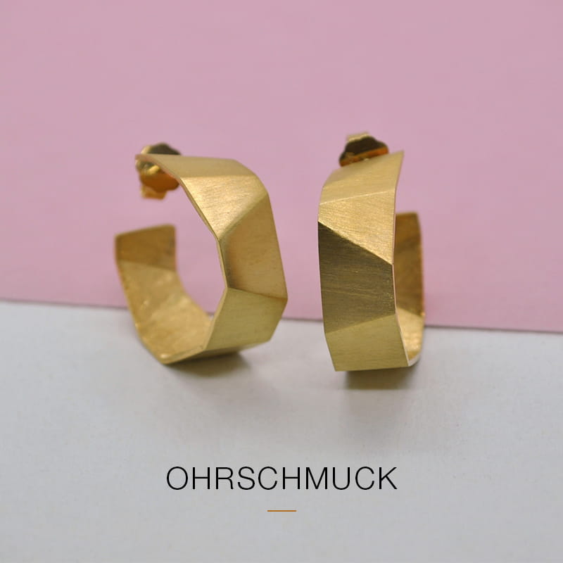 Ein Paar geometrischer, mattgoldener Ohrringe von DOPPELLUDWIG auf rosa-weißem Hintergrund mit dem Schriftzug "OHRschmuck" darunter.