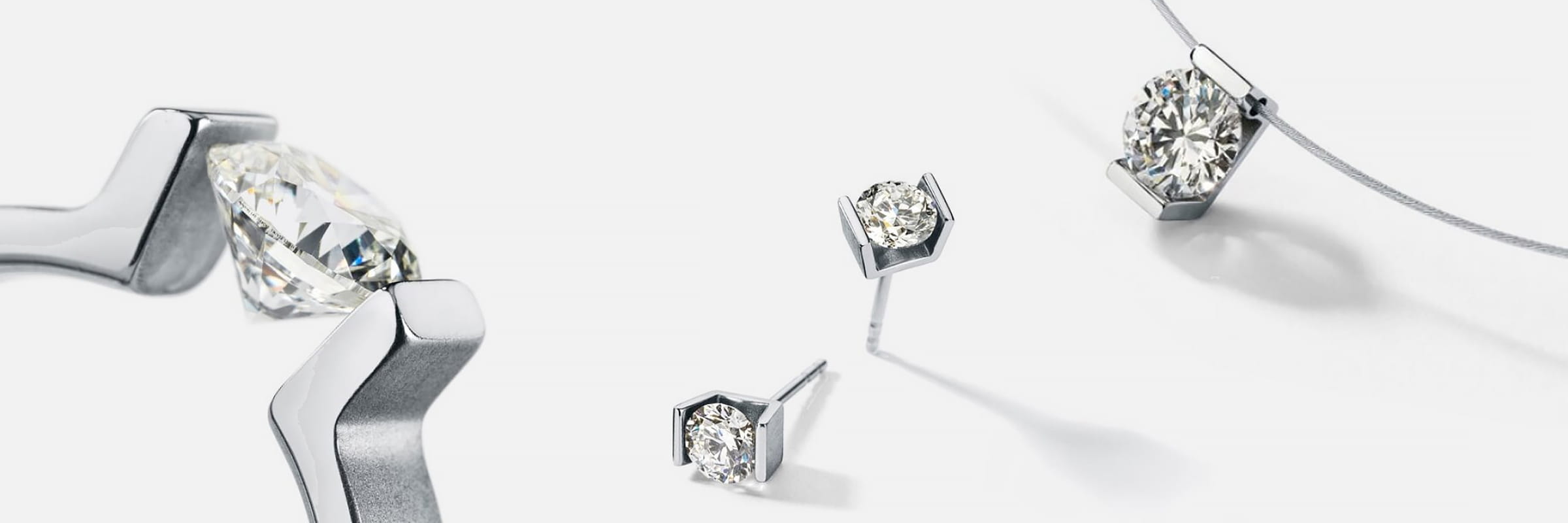 HUMPHREY © 2026 Nahaufnahme von Humphrey-Silberschmuckstücken mit Diamanten im Rundschliff, darunter ein Armband, Ohrstecker und eine Halskette mit Anhänger, alle vor einem sauberen weißen Hintergrund.