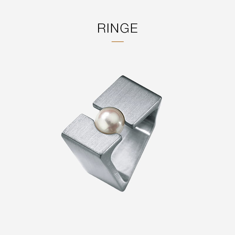 Ein moderner, geometrischer Silberring von Humphrey mit offenem Oberteil und einer einzelnen Perle zwischen den beiden Enden auf einem schlichten weißen Hintergrund mit dem Wort "RINGE" darüber.