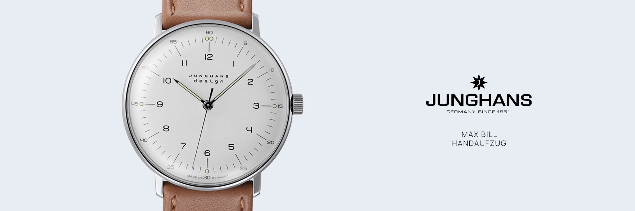Die minimalistische Junghans Max Bill Handaufzug Armbanduhr hat ein weißes Zifferblatt, schwarze Ziffern und ein braunes Lederarmband. Das Junghans-Logo und der Text "Max Bill Handaufzug" erscheinen auf der rechten Seite.
