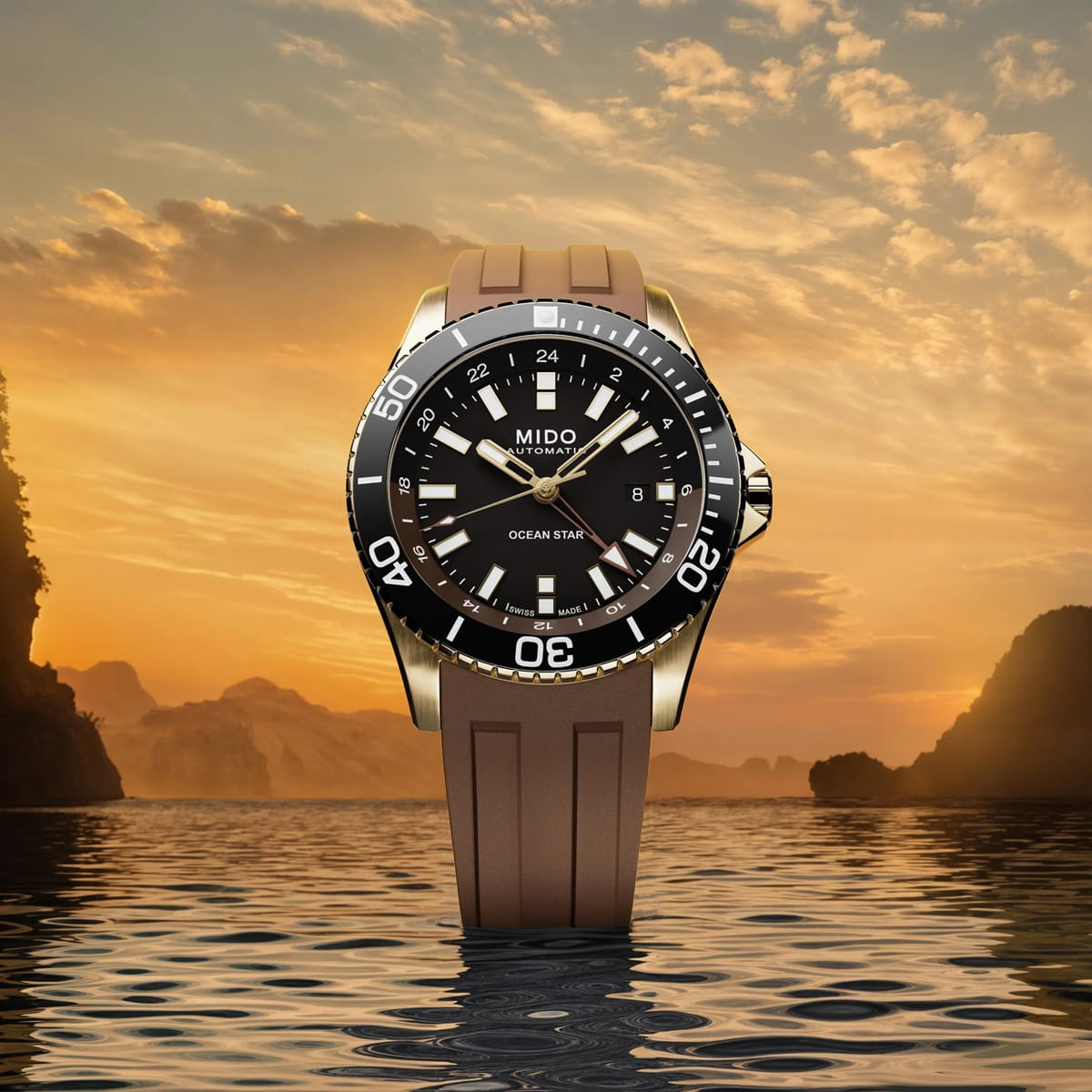 Eine braune Mido Ocean Star Automatikuhr steht aufrecht auf dem ruhigen Wasser, ihre Eleganz wird durch einen dramatischen Sonnenuntergangshimmel und entfernte Felseninseln im Hintergrund unterstrichen.