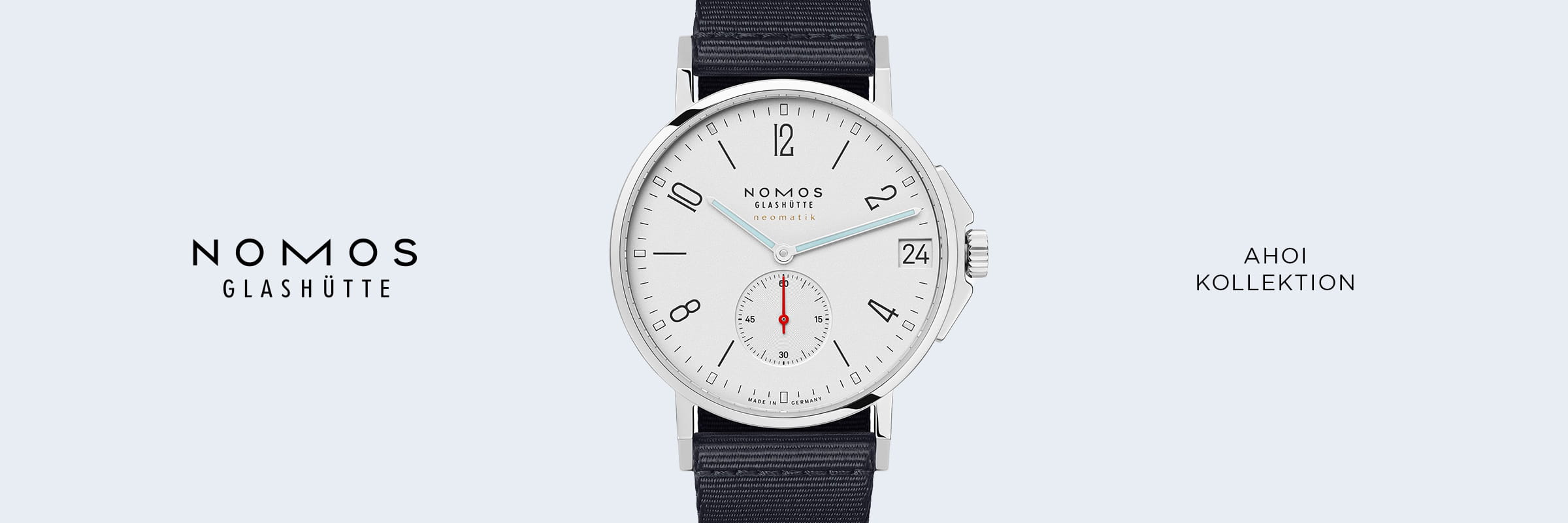 Die silberne NOMOS Glashütte-Armbanduhr aus der NOMOS Ahoi-Kollektion hat ein weißes Zifferblatt, schwarze Ziffern, einen kleinen roten Sekundenzeiger und ein schwarzes Armband zwischen dem NOMOS Glashütte-Logo und der Ahoi-Kollektion" auf hellblauem Grund.