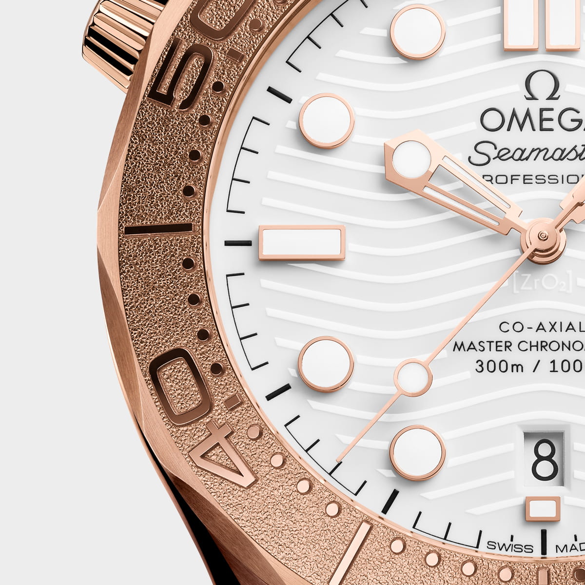 Nahaufnahme einer luxuriösen Omega Seamaster Diver 300M mit einem Gehäuse aus Roségold, einem weißen Zifferblatt mit Wellenmuster, goldenen und weißen Indexen, goldenen Zeigern, einem Datumsfenster bei 6 Uhr und einer Lünette mit eingravierten Ziffern und einer strukturierten Oberfläche.