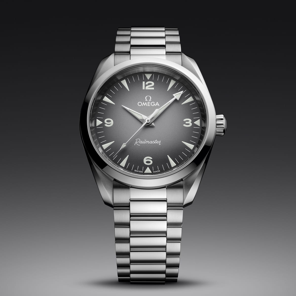 OMEGA © 2026 Eine silberne OMEGA Seamaster Heritage Railmaster Armbanduhr mit Edelstahlarmband, schwarzem Zifferblatt mit Farbverlauf, weißen Zeigern und Ziffern bei 12, 3, 6 und 9 wird vor einem grauen Hintergrund angezeigt.