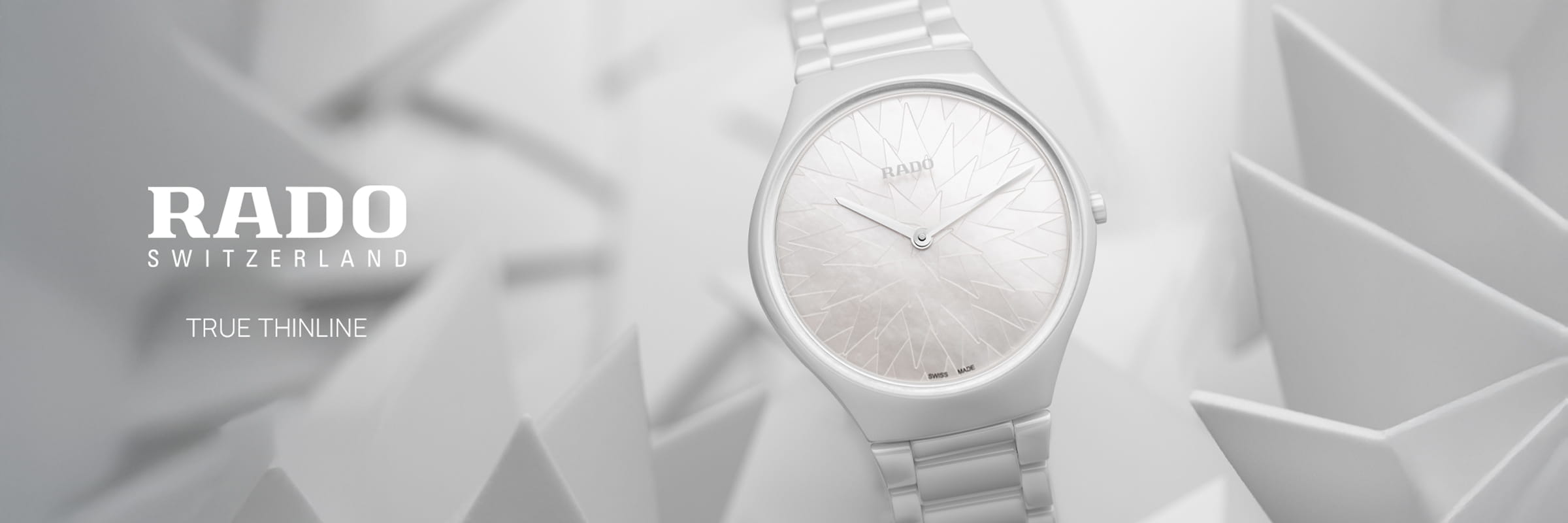 RADO © 2026 Eine Schweizer Uhr RADO True Thinline mit weißem, geometrisch gemustertem Zifferblatt und Metallarmband wird vor einem weißen, abstrakten Hintergrund mit dem Text "RADO SWITZERLAND TRUE THINLINE" auf der linken Seite dargestellt.