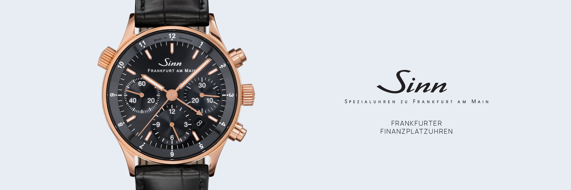Eine Sinn Frankfurt am Main Frankfurter Finanzplatzuhren Armbanduhr mit schwarzem Zifferblatt, Roségoldgehäuse, drei Hilfszifferblättern, Datumsanzeige und schwarzem Lederarmband erscheint neben dem Sinn-Logo und deutschem Text auf hellem Grund.