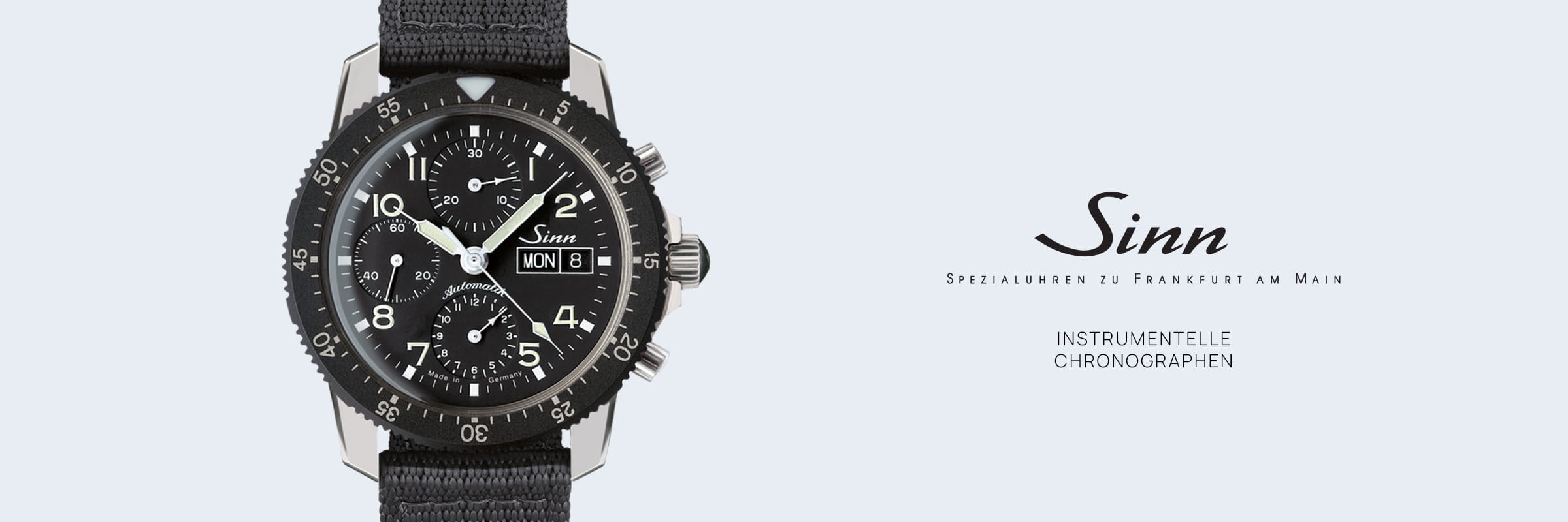 SINN Spezialuhren © 2026 Auf der linken Seite ist eine schwarze Sinn-Chronographen-Uhr mit einem Nylonband abgebildet. Auf der rechten Seite sind das Sinn-Logo und der Text abgebildet: "Spezialuhren zu Frankfurt am Main" und "Instrumentelle Chronographen" auf hellem Grund.