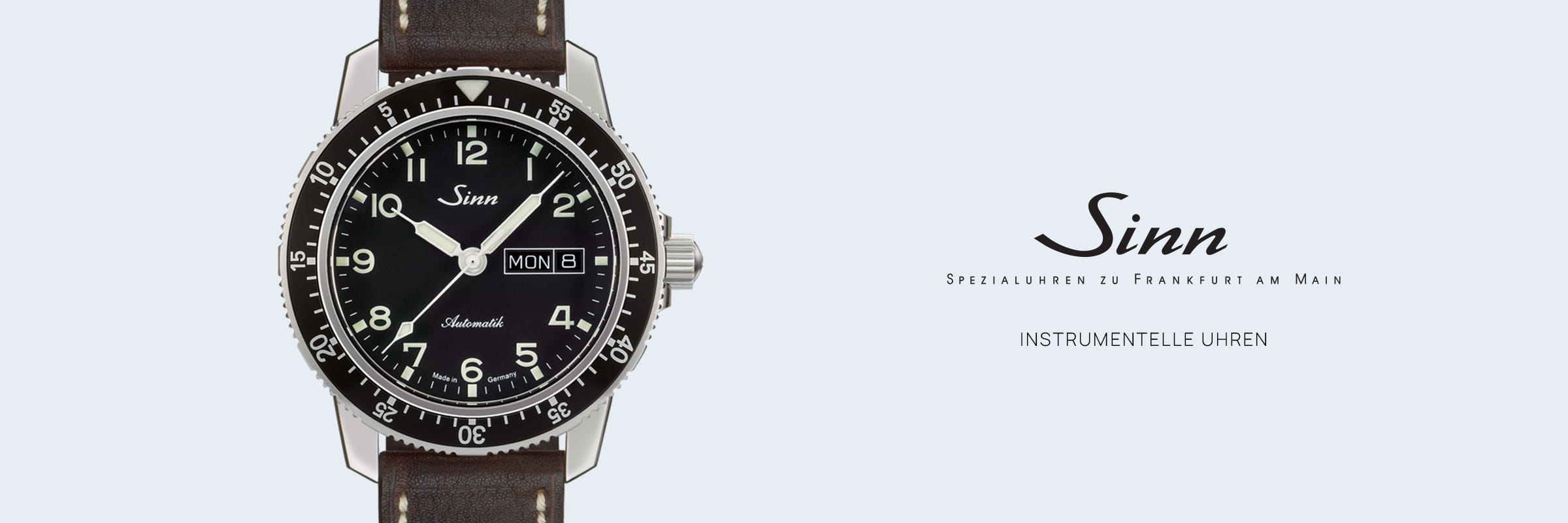 SINN Spezialuhren © 2026 Auf der linken Seite ist eine Sinn Instrumentelle Uhren Armbanduhr mit schwarzem Zifferblatt, weißen Ziffern und braunem Lederarmband zu sehen. Auf der rechten Seite weisen das Sinn-Logo und der deutsche Text auf die Spezialität und den Standort des Uhrenherstellers hin.